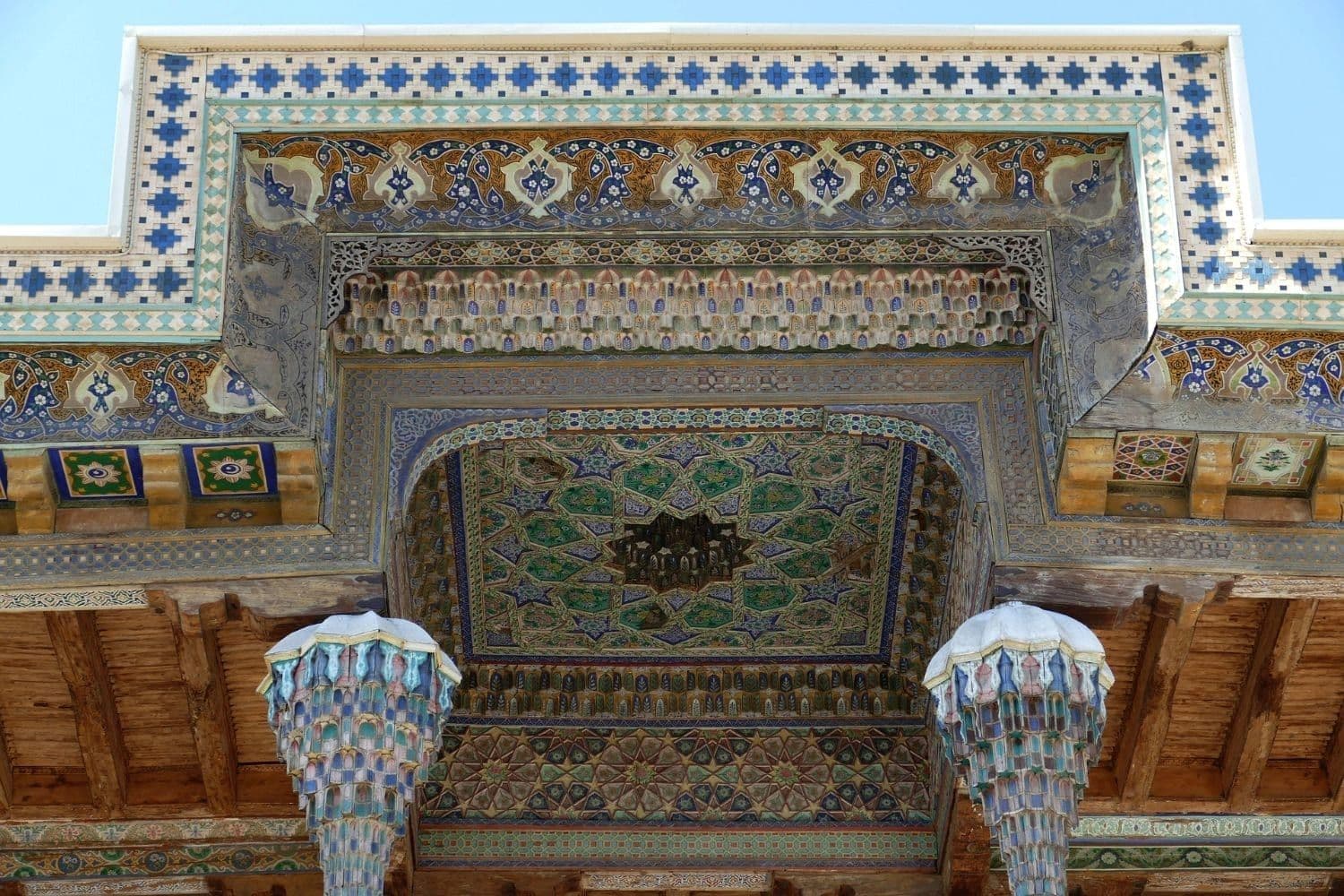 Painted ceiling of the Bolo Hauz mosque in Bukhara: star patterns and colourful stalactite capitals atop wooden columns