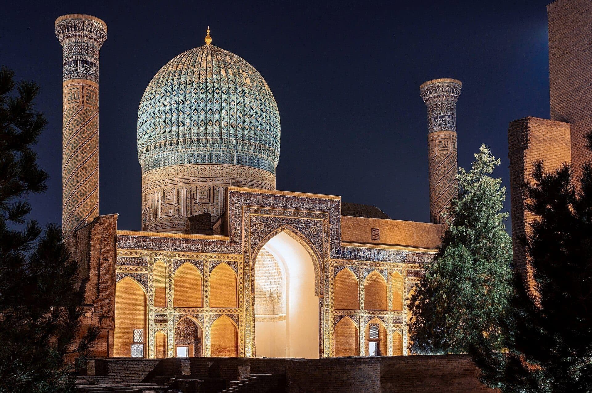 Tunda yoritilgan Go‘ri Amir — Samarqanddagi Amir Temur maqbarasi: qovurg‘ali feruza gumbaz, ikki minora va nurli peshtoq