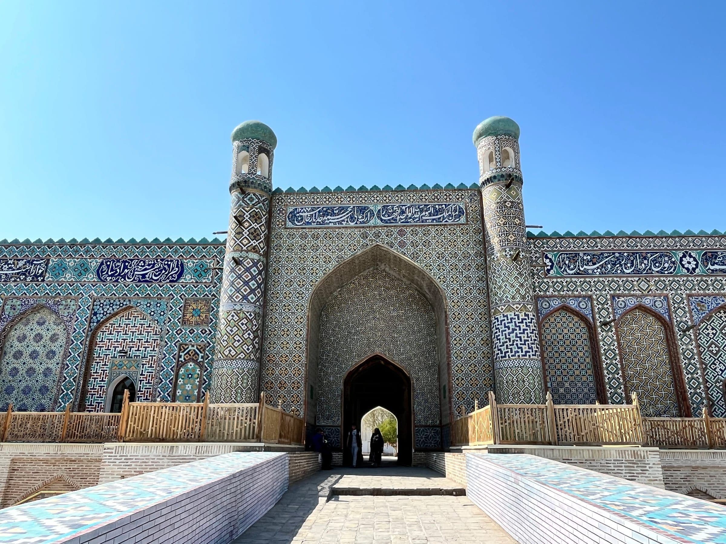 Tiled main portal of Khudayar Khan's palace in Kokand, with bands of calligraphy and two slender turquoise-capped towers