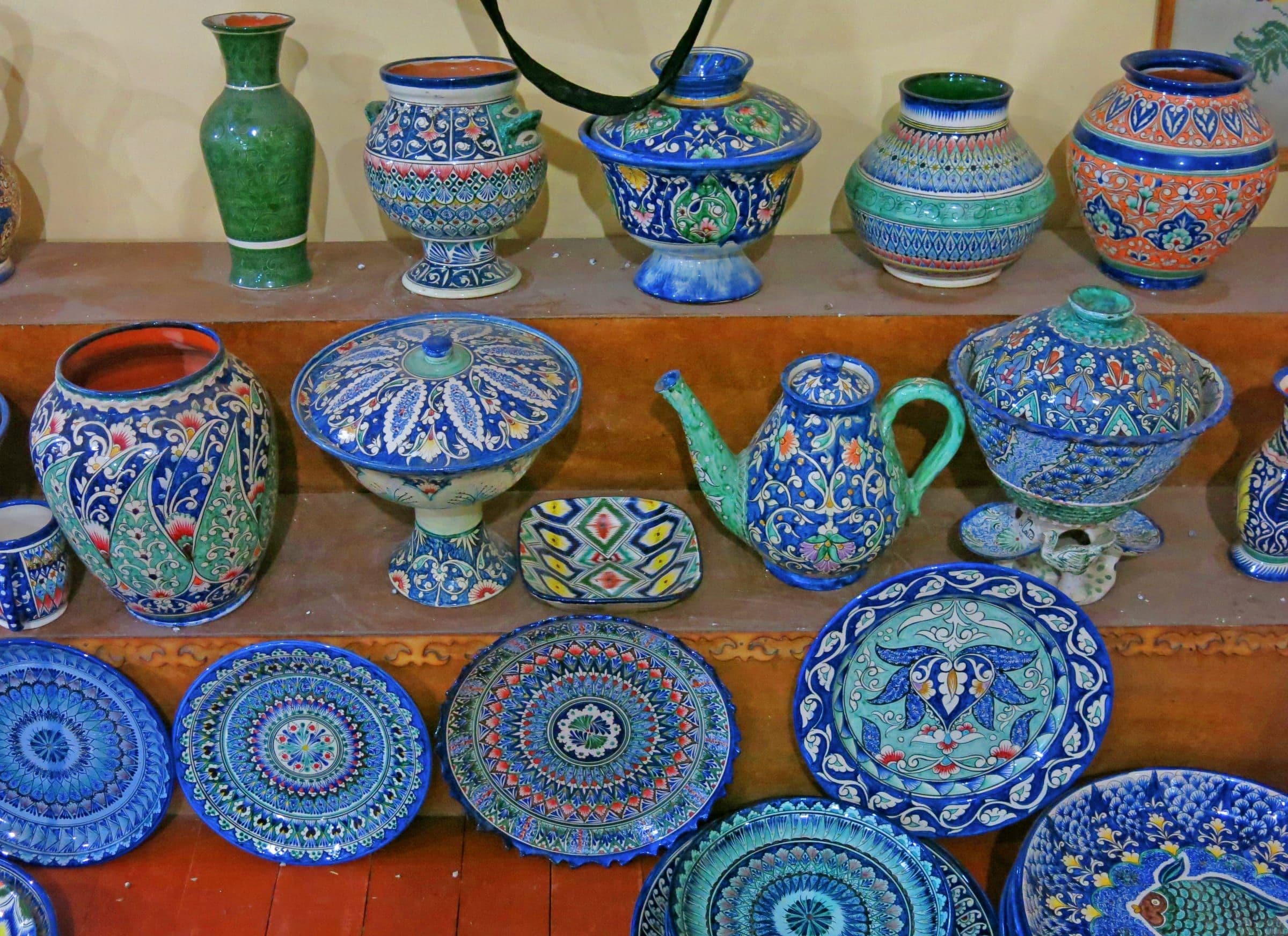 Rishtan ceramics on shelves: vases, lidded bowls, a teapot and plates painted in deep blue and turquoise glaze