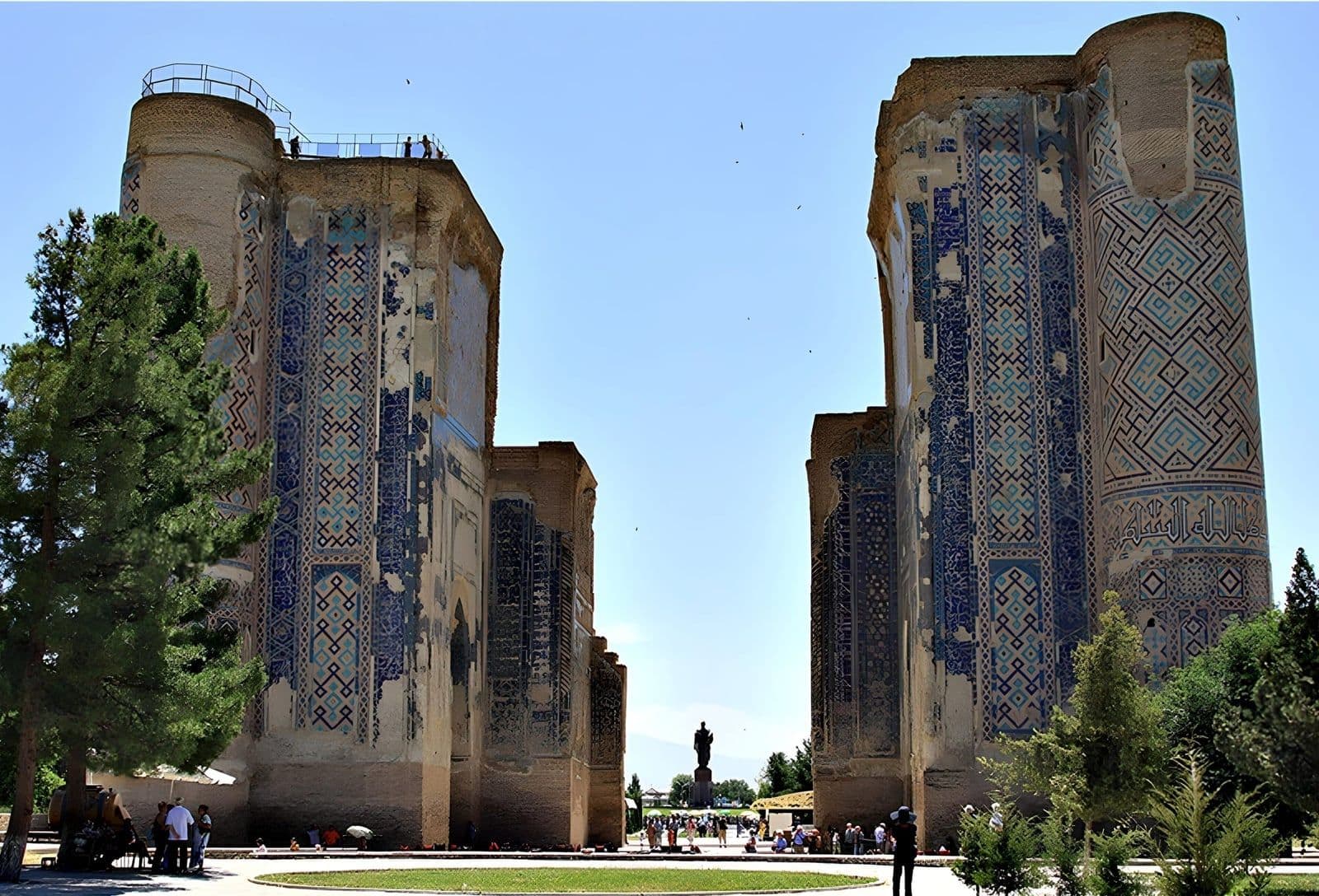 Ak-Saray, Shakhrisabz: the two ruined, tile-clad gate towers of Timur's palace, with his statue seen through the gap